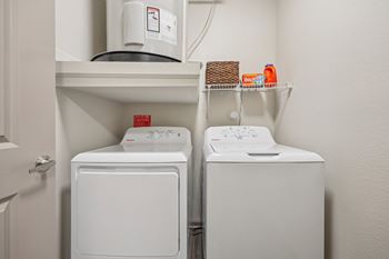 A white dryer and washer are on a shelf in a laundry room.